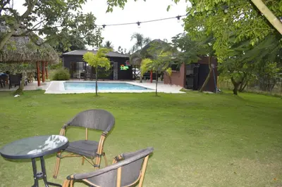 two chairs and a table in a yard with a pool at Villa Doña Plinia in El Cruce