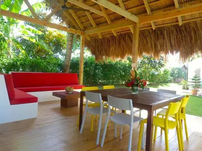 a patio with a table and chairs and a red couch at Charming oceanside 2 bd villa in Cabarete