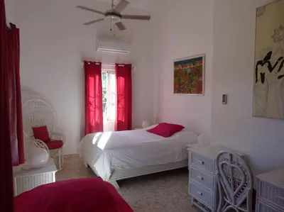 a bedroom with a white bed and red curtains at Charming oceanside 2 bd villa in Cabarete