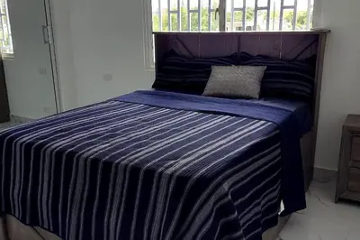 a bed with a blue striped comforter in a room at Bocachica house,apts,village in Jubey