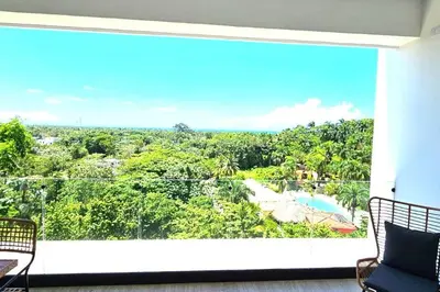a balcony with a view of a pool and trees at New 2 BR apt with swimming pool at playa bonita in Las Terrenas