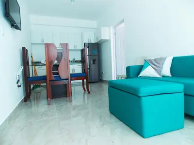 a living room with a blue couch and a kitchen at Residencial Victoria in Sampiño