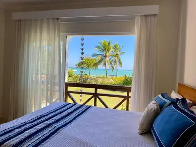 a bedroom with a bed and a view of the beach at Blue View Beachfront Apartment with Ocean View in Sampiño