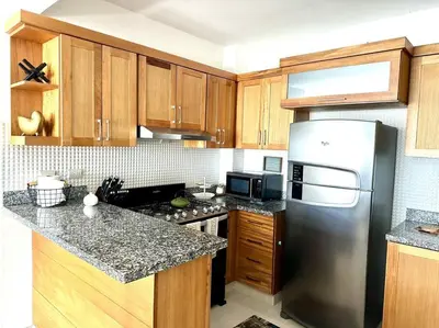 a kitchen with wooden cabinets and a stainless steel refrigerator at Vista Panorama Cipres in Hato Mayor