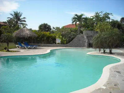 a swimming pool in a resort with palm trees at Bluefish Condo, Ocean Front, Sunrises, Pool, Hot Tub, Under New Management in Sosúa