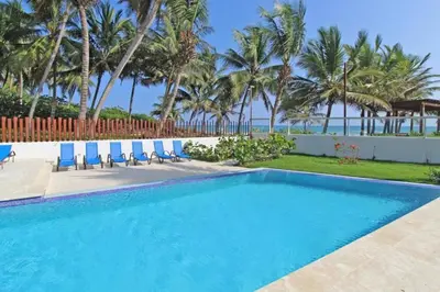 a swimming pool with blue chairs and palm trees at Direct View and Access to Beach! in Eslabón