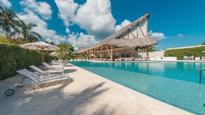 a swimming pool with chairs and umbrellas next to a resort at Apartment nearby the beach at Portillo RAA in Las Terrenas