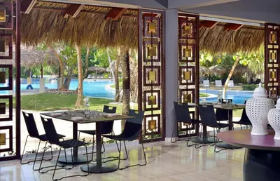 a restaurant with tables and chairs and a pool at Paradisus Punta Cana Resort All Inclusive in Punta Cana