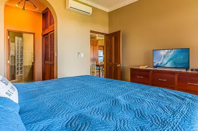 a bedroom with a blue bed and a flat screen tv at Truly Beachfront at Quiet Beach in Cabarete