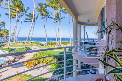 a balcony with palm trees and the ocean at Truly Beachfront at Quiet Beach in Cabarete