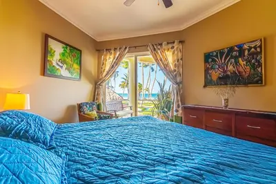 a bedroom with a blue bed and a window at Truly Beachfront at Quiet Beach in Cabarete