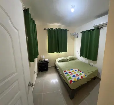 a small bedroom with green curtains and a bed at Tu casa los frailes 2da in La Alianza