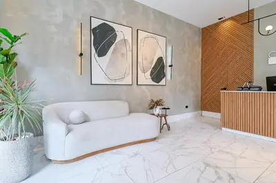 a living room with a white couch and paintings on the wall at Cozy, Centric 1BR Condo, Pool in Los Prados