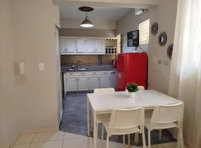 a kitchen with a white table and chairs and a red refrigerator at Apartamento próximo al centro médico HOMS in Hato Mayor
