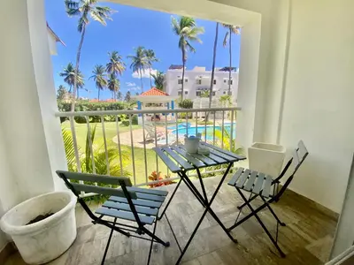 a balcony with a table and chairs and a view of the pool at The Perfect Place for Holiday in los Corales RD in Punta Cana