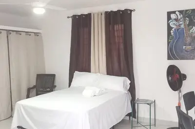 a bedroom with a white bed and a chair at Aparta estudio 2 El Cacique, próximo malecón SD in Santo Domingo