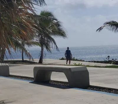 a man standing next to a bench near the ocean at Aparta estudio 2 El Cacique, próximo malecón SD in Santo Domingo