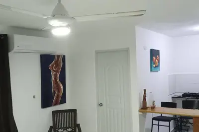 a living room with a ceiling fan and a white wall at Aparta estudio 2 El Cacique, próximo malecón SD in Santo Domingo