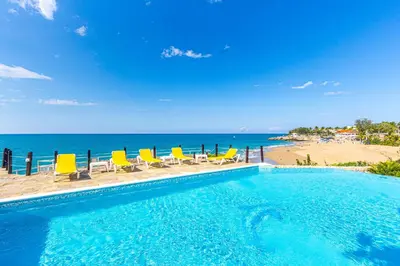 a swimming pool with chairs and a beach at Los Balcones, Sosua, Ocean Front! in Sosúa