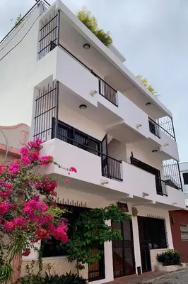 a white building with balconies and pink flowers at Casa La Maria Zona Colonial in Santo Domingo