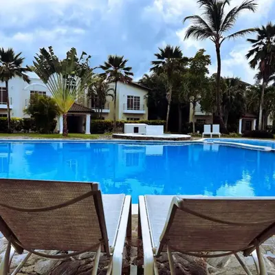 two chairs sitting in front of a swimming pool with palm trees at Apartamento en Punta Cana, White sands in Punta Cana