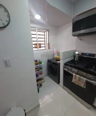 a kitchen with a stove and a clock on the wall at Apartamento Residencial sembrador 3 ciudad Juan Bosch in La Javilla