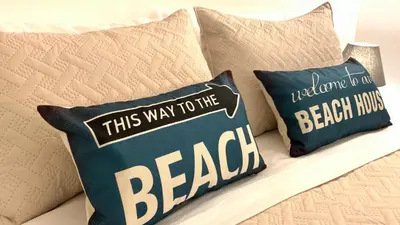 a couple of pillows on a couch with the words this way to the beach at Beachfront Unit with Stunning Sunsets and Starlink Internet ! in Las Terrenas