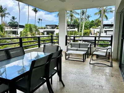 a balcony with a table and chairs and palm trees at Beachfront complex 3BD 3BA with pool in Las Terrenas