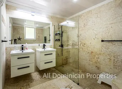 a bathroom with two sinks and a glass shower at Hispaniola Beach Official, Sosua! in Sosúa