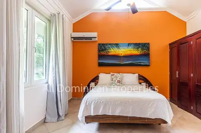 a bedroom with an orange wall and a bed at Hispaniola Beach Official, Sosua! in Sosúa