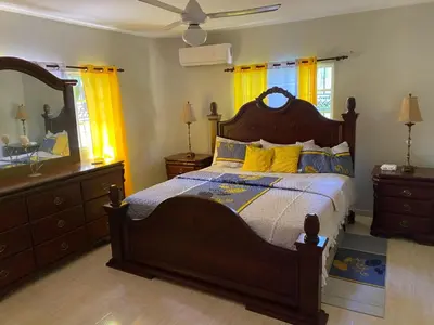 a bedroom with a large wooden bed with yellow pillows at My home in San Felipe de Puerto Plata