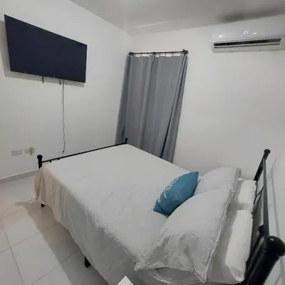a bedroom with a bed and a flat screen tv at Santo Domingo Este in Ensanche Savica de Mendoza