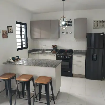 a kitchen with a black refrigerator and some bar stools at Santo Domingo Este in Ensanche Savica de Mendoza
