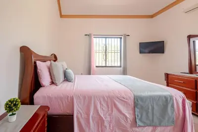 a bedroom with a bed with pink sheets and a dresser at Eden House in Río San Juan