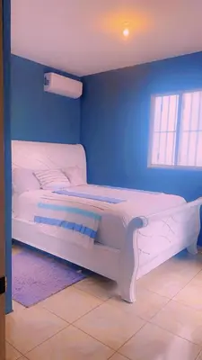 a white bed in a room with a blue wall at Casita Azul in Isabel de Torres