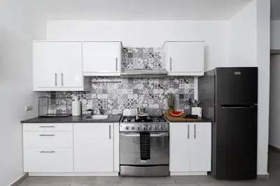 a white kitchen with a stove and a refrigerator at Coastal Luxury 2-Bed w Pool Access in Paraiso Bayahibe in Bayahibe