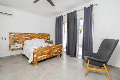 a bedroom with a bed and a chair and window at Coastal Luxury 2-Bed w Pool Access in Paraiso Bayahibe in Bayahibe