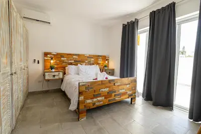 a bedroom with a large bed with a wooden headboard at Coastal Luxury 2-Bed w Pool Access in Paraiso Bayahibe in Bayahibe