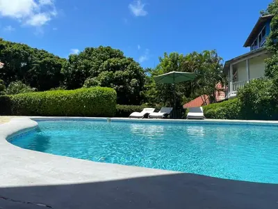 a swimming pool with two chairs and an umbrella at Villa Michel in Laguna del Higüero