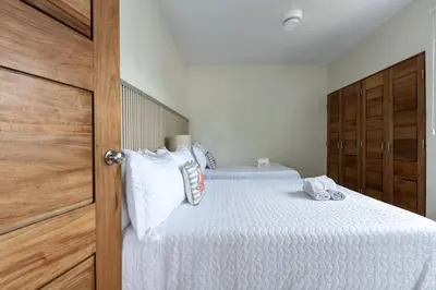 a bedroom with two beds with white sheets and a wooden door at Caribey 2, Las Terrenas in Las Terrenas