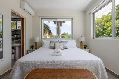 a bedroom with a large white bed with two windows at Caribey 2, Las Terrenas in Las Terrenas