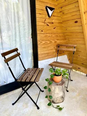 two wooden chairs and a table and a plant at Leisy's Garden Hostel & Rooms in Santa Bárbara de Samaná