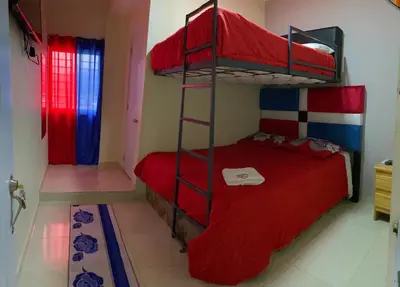 a bedroom with two bunk beds with red sheets at Hotel El Parque Constanza in Constanza