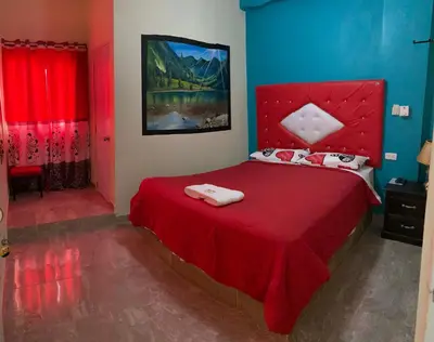 a bedroom with a red bed with two towels on it at Hotel El Parque Constanza in Constanza
