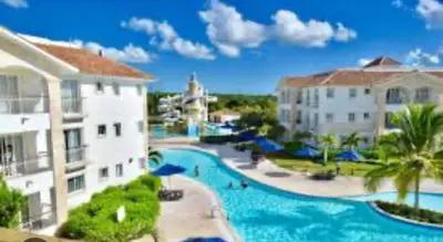 a resort with a large swimming pool next to two buildings at Cadaques Caribe Palmera 101 in Bayahibe