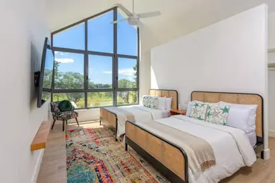two beds in a room with a large window at Villa Polos, Prestigious Haven In Casa De Campo in La Romana