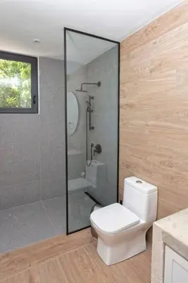 a bathroom with a toilet and a glass shower at Villa Polos, Prestigious Haven In Casa De Campo in La Romana