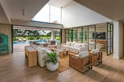 a large living room with white furniture and a pool at Villa Polos, Prestigious Haven In Casa De Campo in La Romana