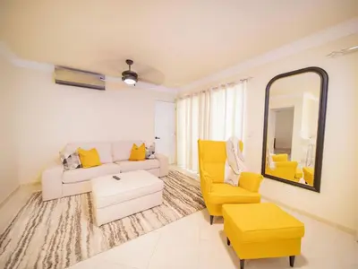a living room with a white couch and yellow chairs at Garden Condos 21, Modern 1BR APT In Sosua Strip GUEST FRIENDLY in Sosúa