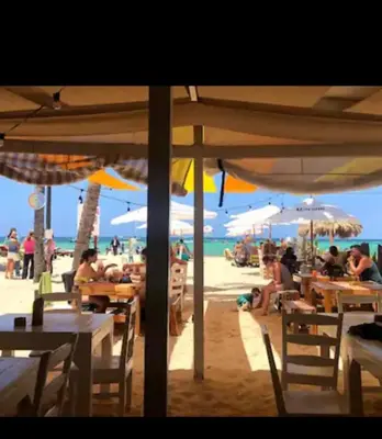 people sitting at tables on the beach under umbrellas at The Best Place in los Corales RD Arenas De B in Punta Cana